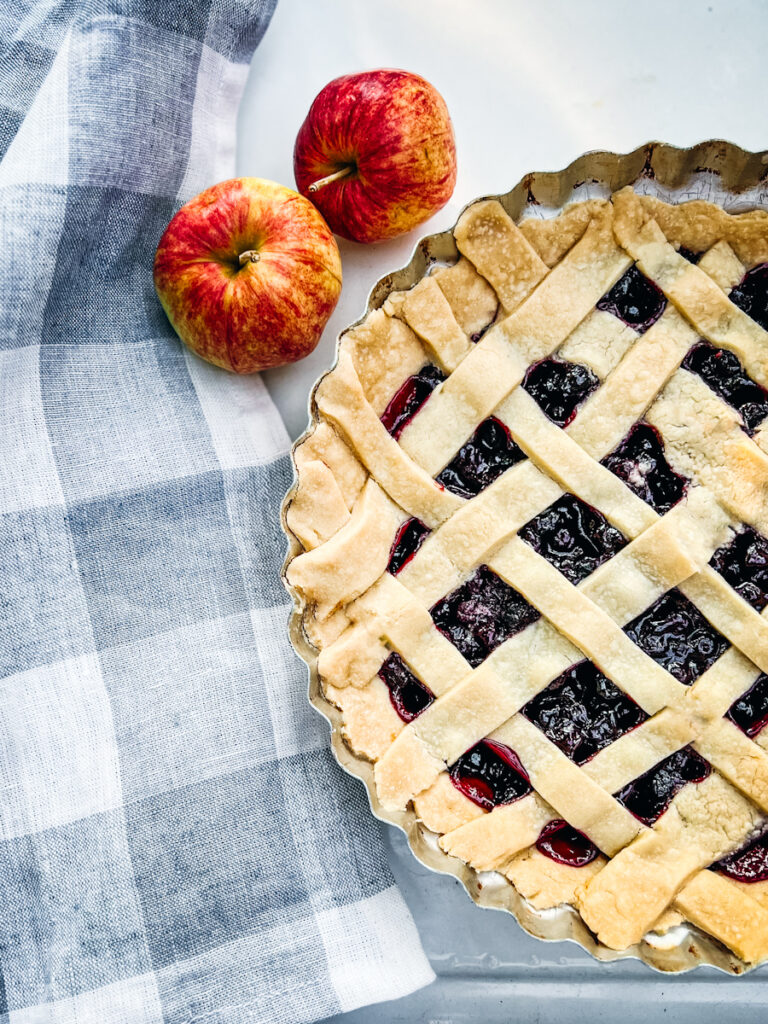 Saskatoon berry pie that is fresh baked and with a blue and white checkered tablecloth.