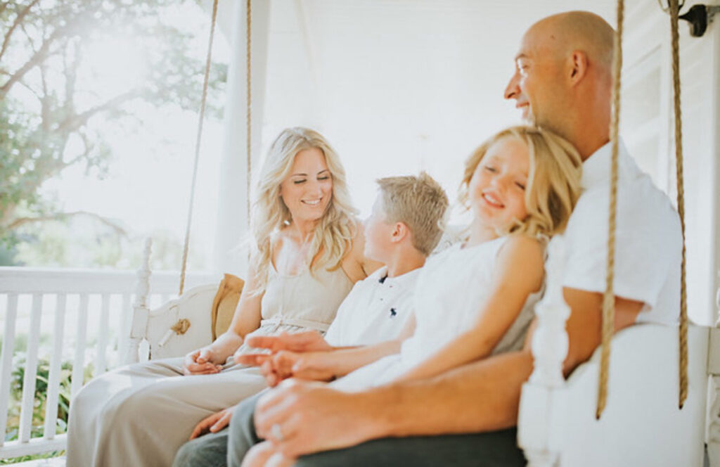 A family enjoying their porch swing on the front porch. 