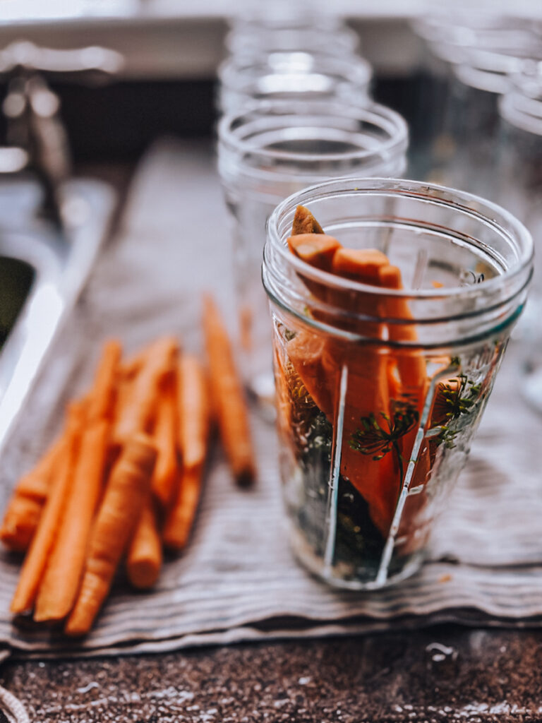 Stuffing jars full of carrots to pickle