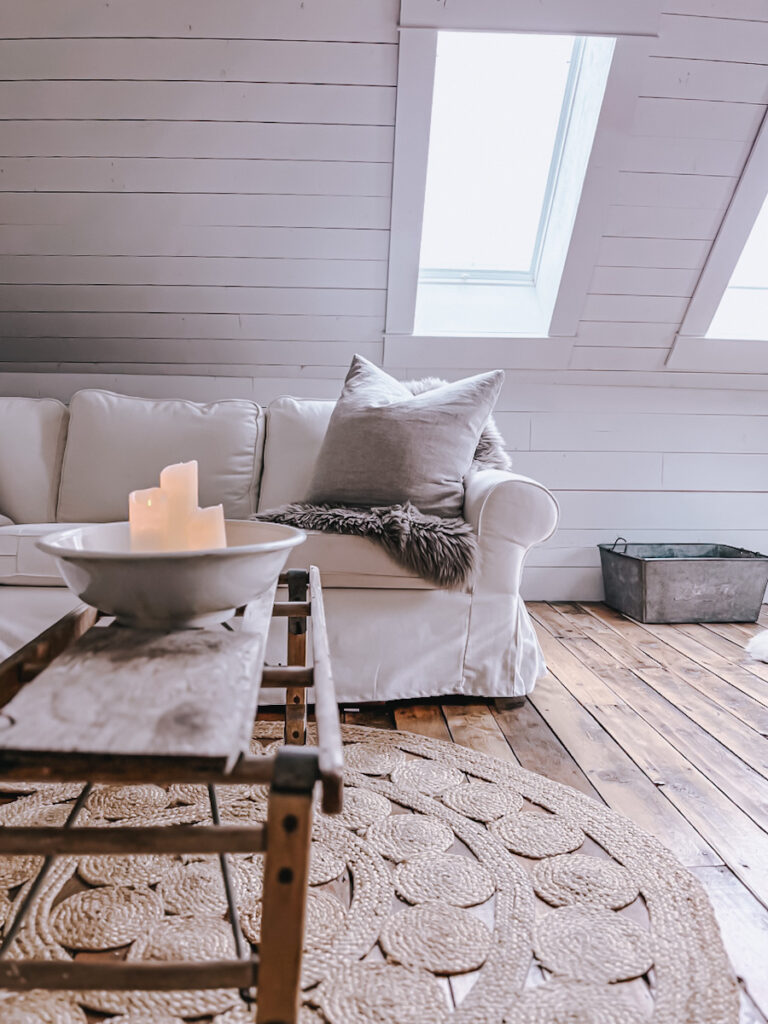Linen pillows on a white sofa with a gray sheepskin rug. .