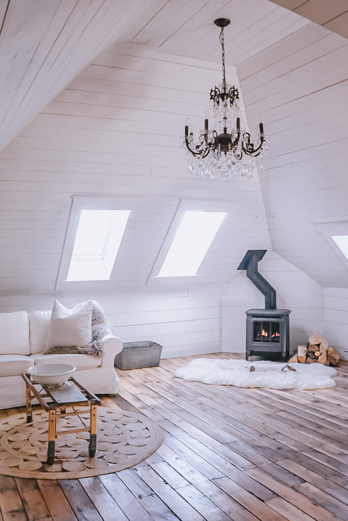 Beautiful high ceilings in an attic space family room with a fireplace and a large chandelier .