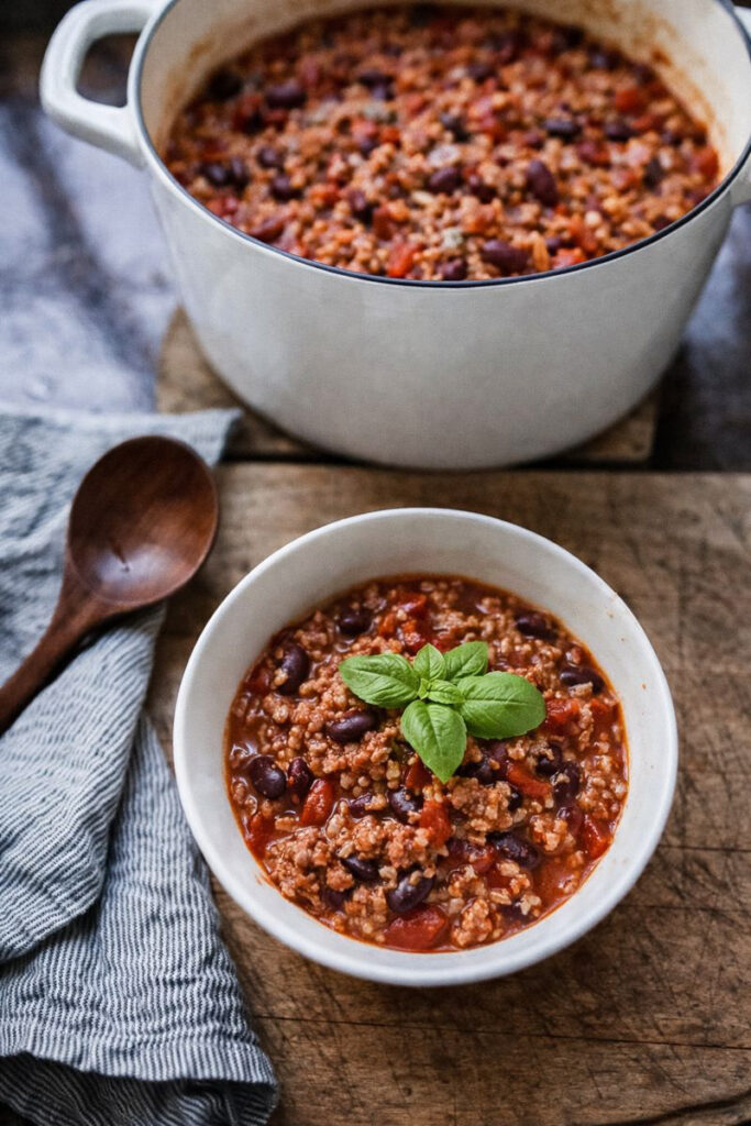 Dutch oven chili being served in a white bowl.