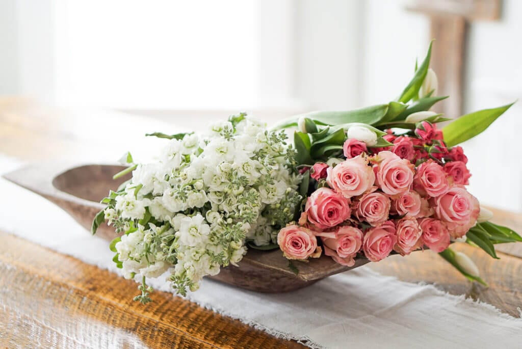fresh cut roses and flowers in an antique dough bowl