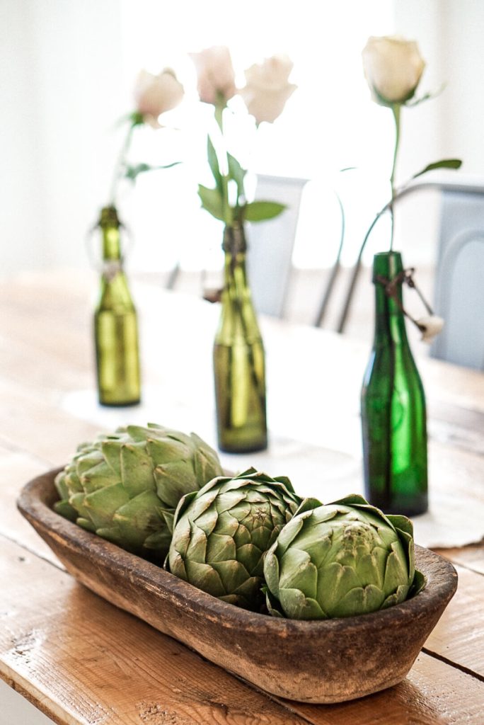 Green Bottles and artichokes in a vintage bread prover for winter decoations