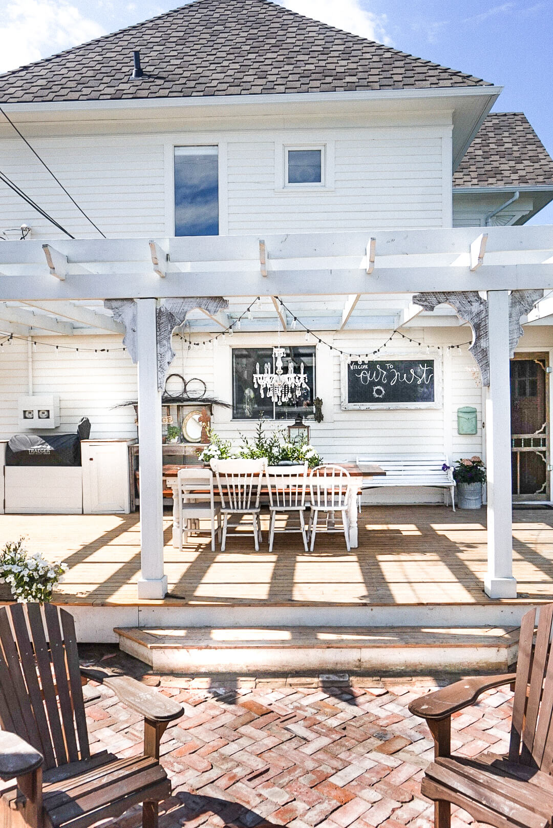 white house with a large pergola and farmhouse patio