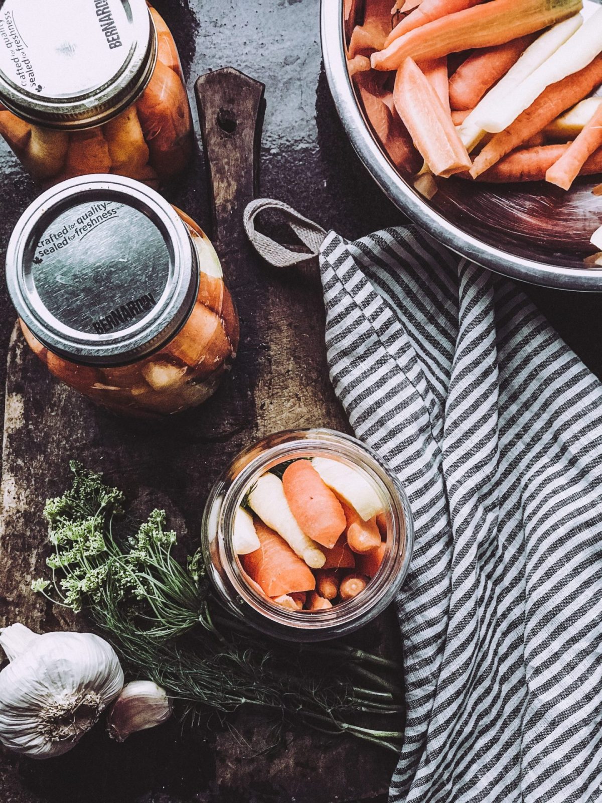 pickled carrots on a antique cutting board with dill and fresh garlic pickled carrots on a antique cutting board with dill and fresh garlic