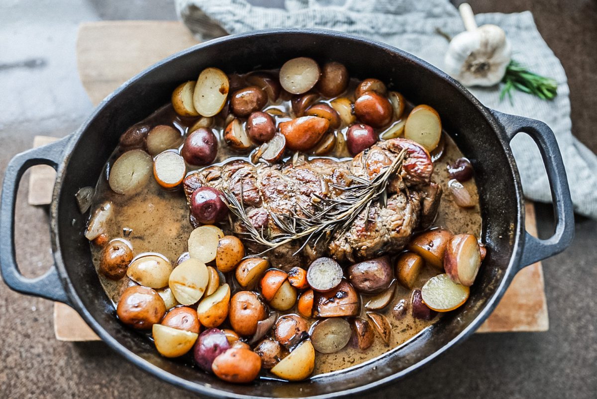 cooked roast beef and potatoes in a cast iron dish juice fully cooked fall apart top round roast