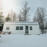 white tiny house cabin made from a garden shed in the winter