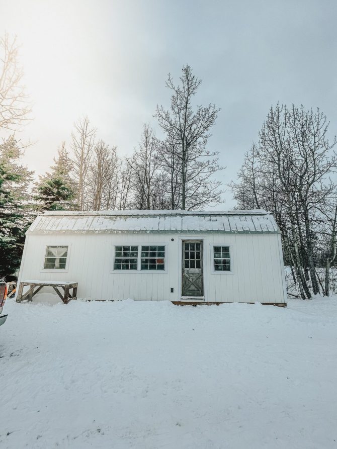 white tiny house cabin made from a garden shed in the winter