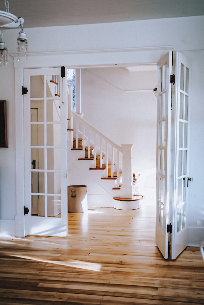 Triple French doors overlooking a beautiful white and fir wood staircase in an old house. 