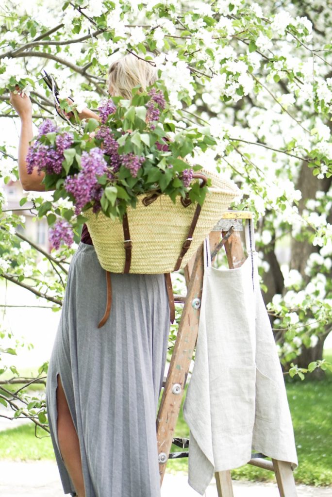 home decor quiz Girl cutting a blooming tree with lilac blossoms in her market basket backpack