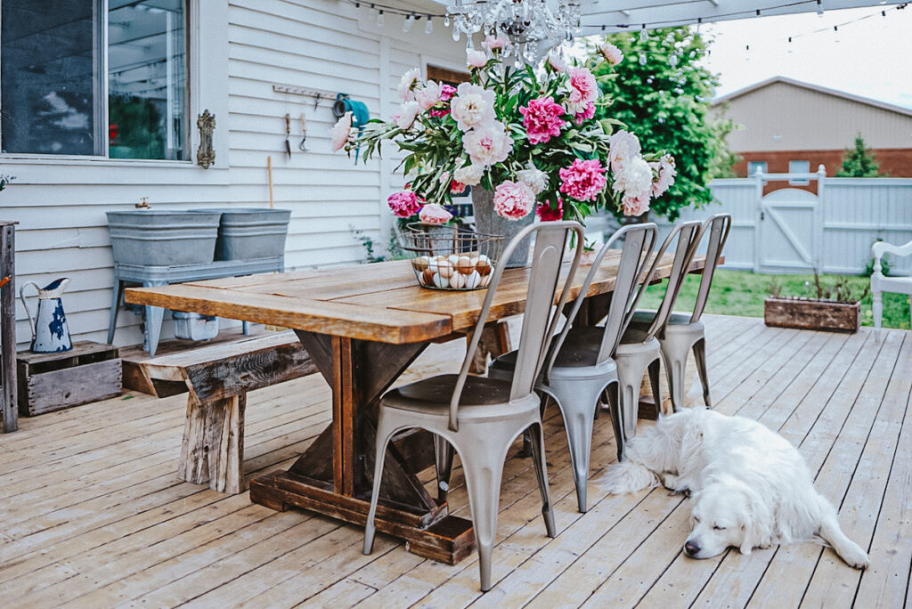 A farmhouse table with metal French cafe chairs on an outdoor patio.