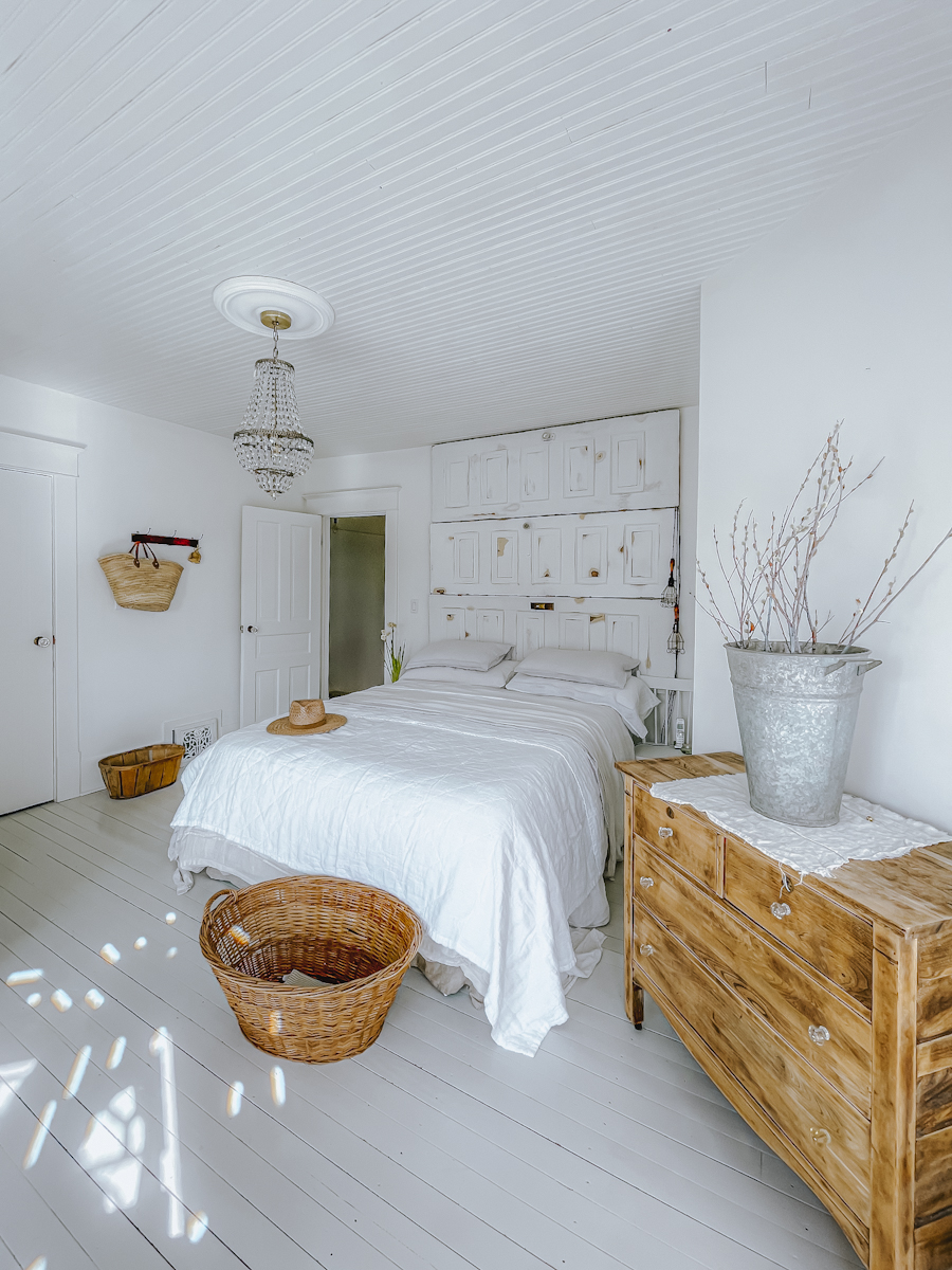 white bed in a master bedroom with painted floors
