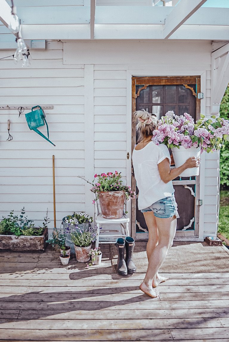 girl carrying lilacs on a patio with flower pots displayed