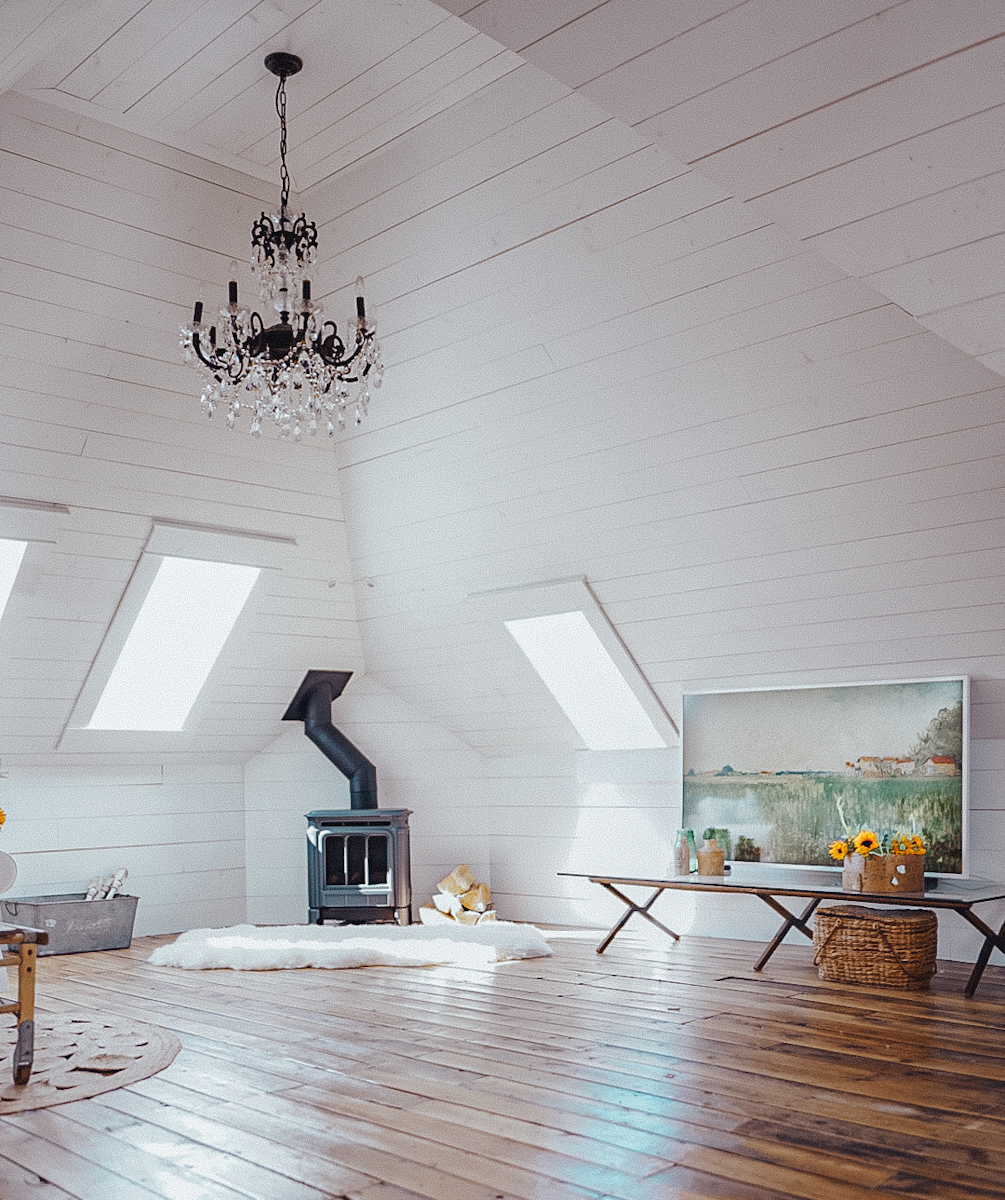 shiplap attic space with a vaulted ceiling and afree standing fire place and chandelier