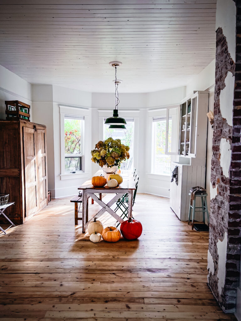 A dining room decorated with autumn natural elements like hydrangeas and pumpkins.
