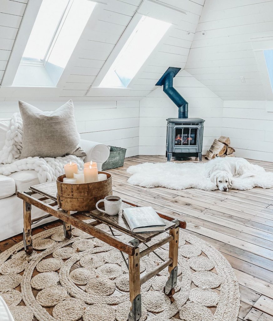 a cozy family room with a wood burning stove and sheepskin rug beside a sofa with a chunky knit throw