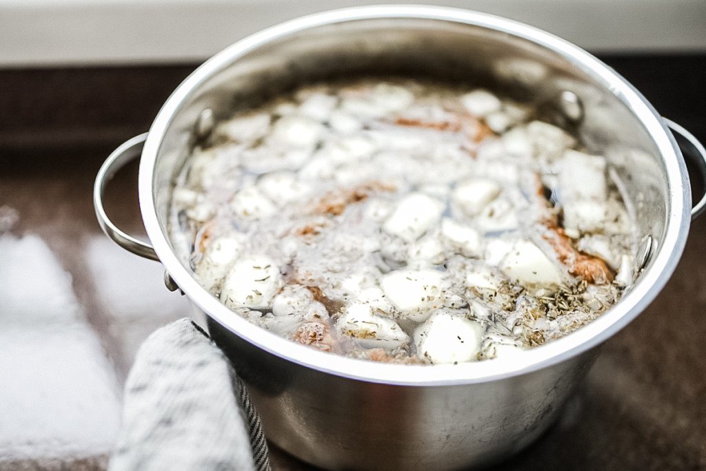 chicken broth in a pot with bones and onions