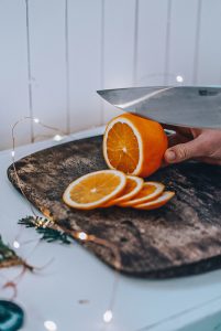 thinly cutting orange slices with a sharp knife on a cutting board