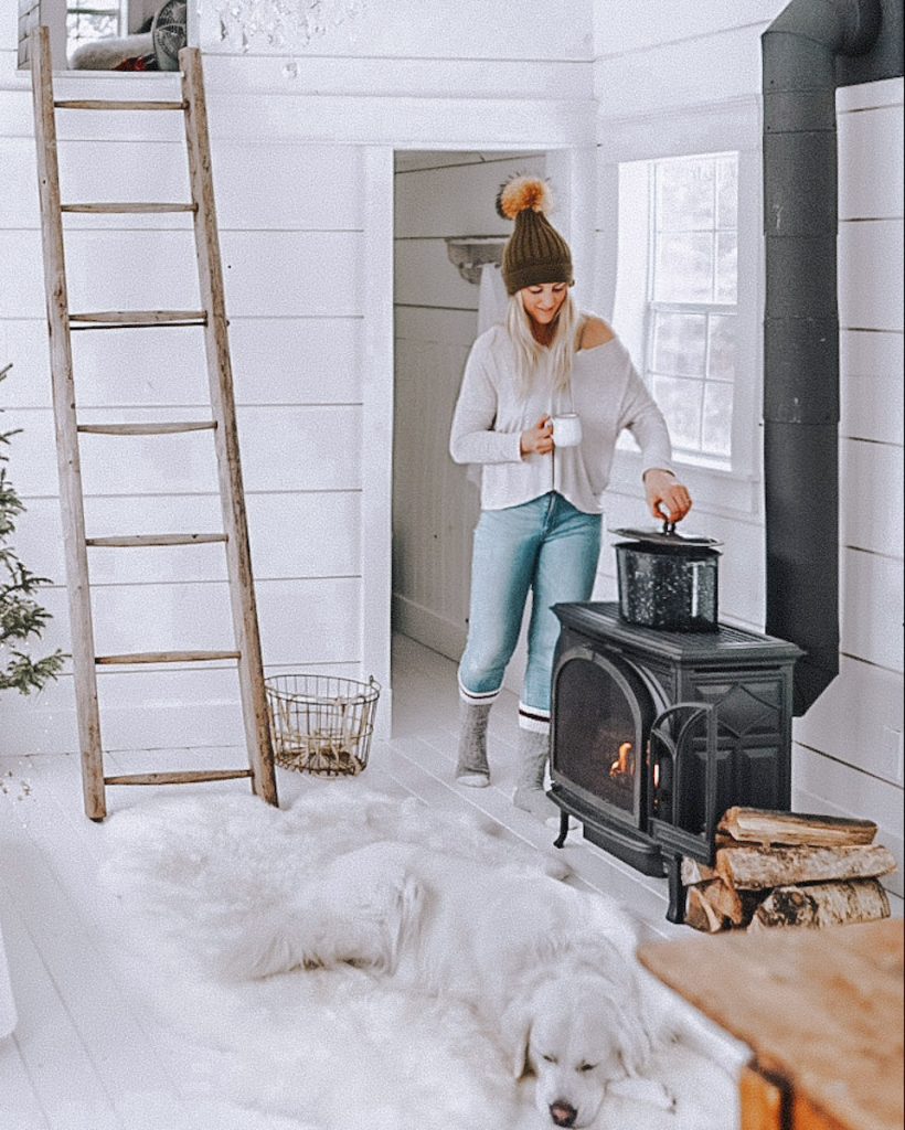 simple winter decor at a cabin with a girl getting water off a hot stove pot.