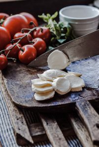 cutting mozzarella on a cutting board with a chefs knife