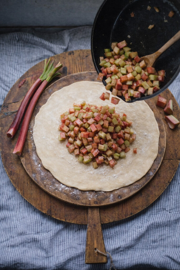 Placing the rhubarb filling on a rolled-out pie crust, 