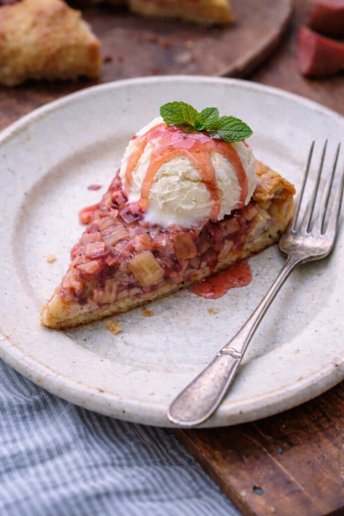 Slice of Rustic Rhubarb Galette with vanilla ice cream and rhubarb syrup on top. 