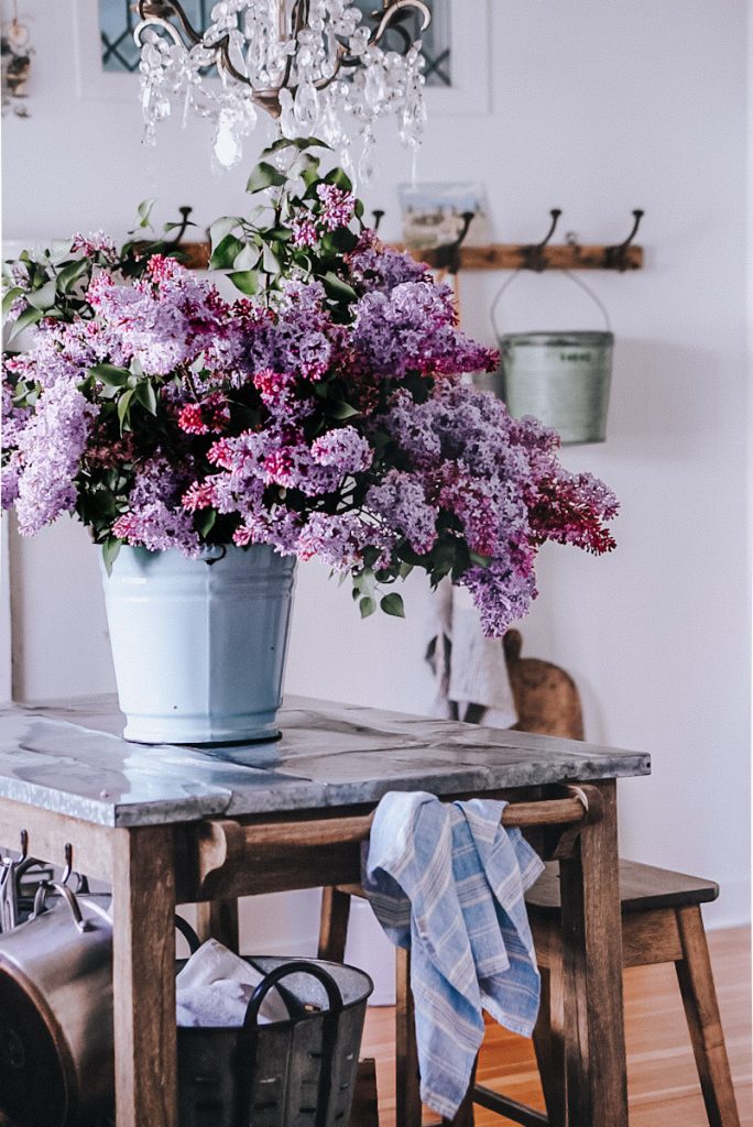 a beautiful bouquet of lilacs on a farmhouse kitchen island with a blue linen towel