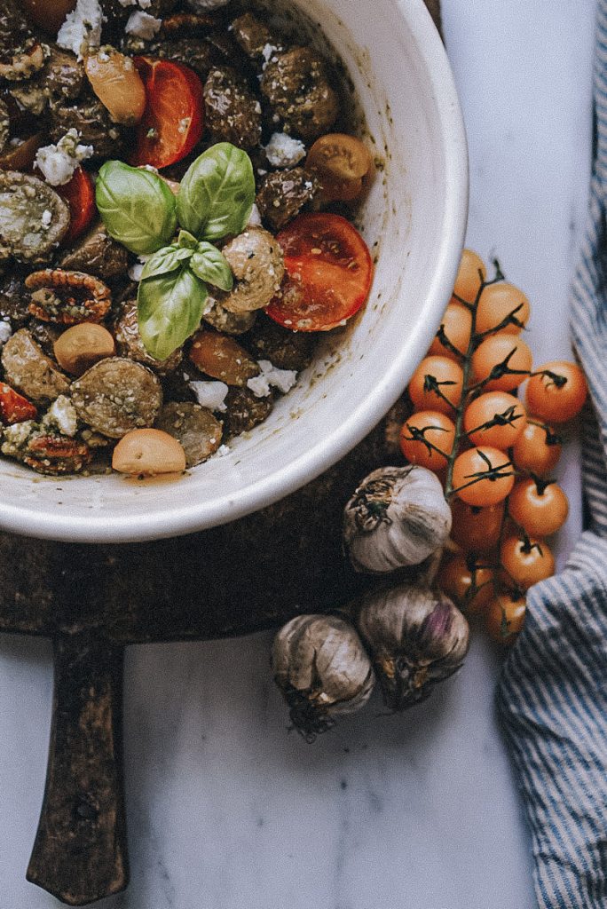 pesto potato salad in an antique bowl on a cutting board in
