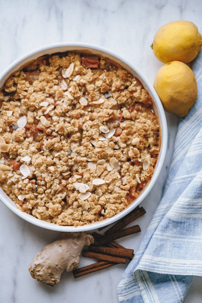 baked rhubarb and ginger crumble with fresh lemons and ginger beside it