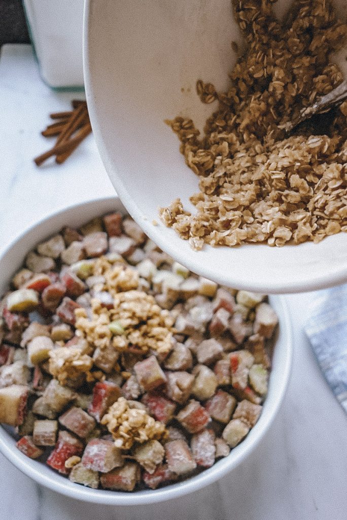 adding crumble topping on top of the filling for a rhubarb and ginger crumble