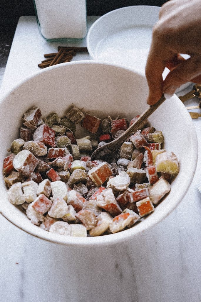 mixing the filling for rhubarb and ginger crumble in a a large mixing bowl