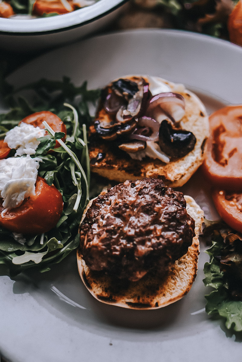 bison burger patty on a bun with mushrooms and shallots