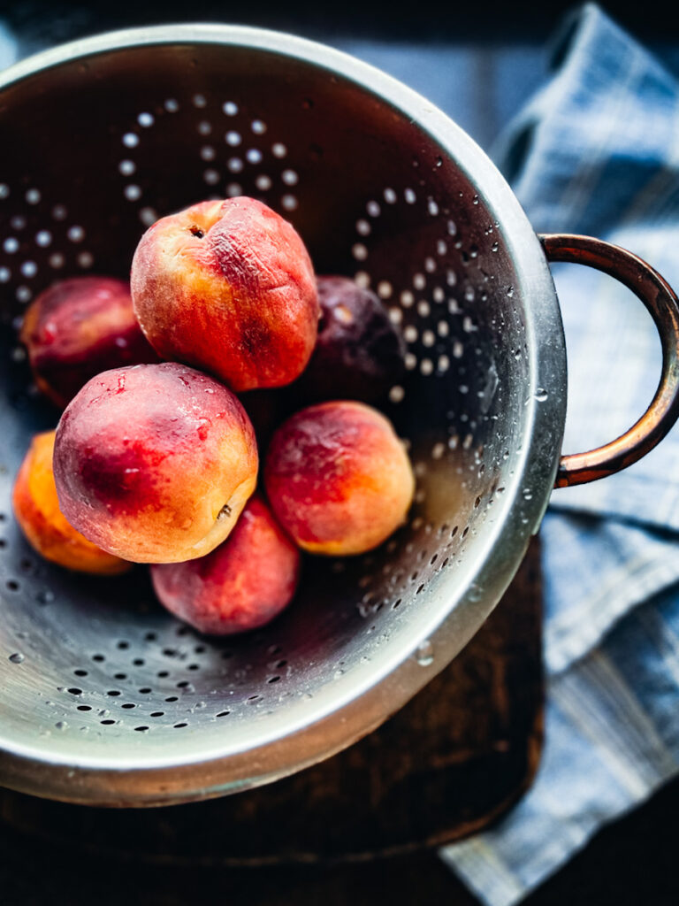 Peaches washed and ready and a strainer to be made into peach crumble.