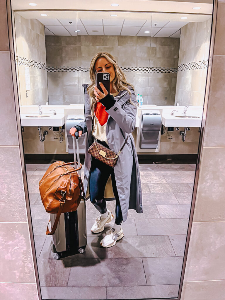 Deborah from B Vintage in an airport taking a selfie with a leather duffle bag 