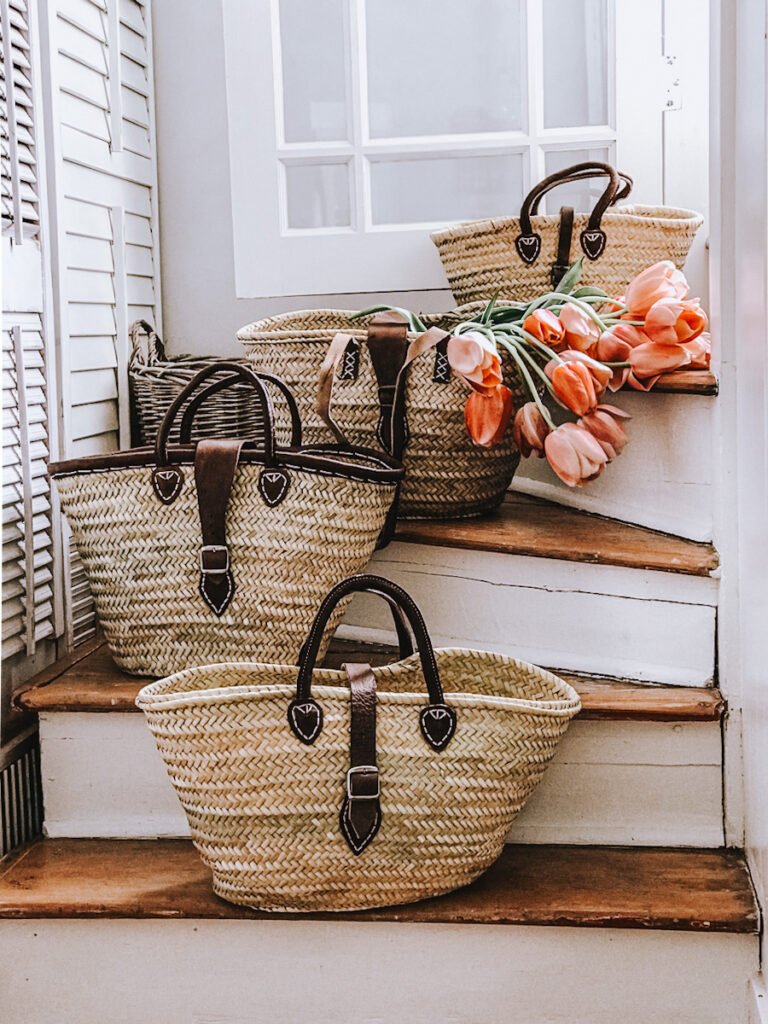 Different styles of French market baskets on a staircase with tulips in them .