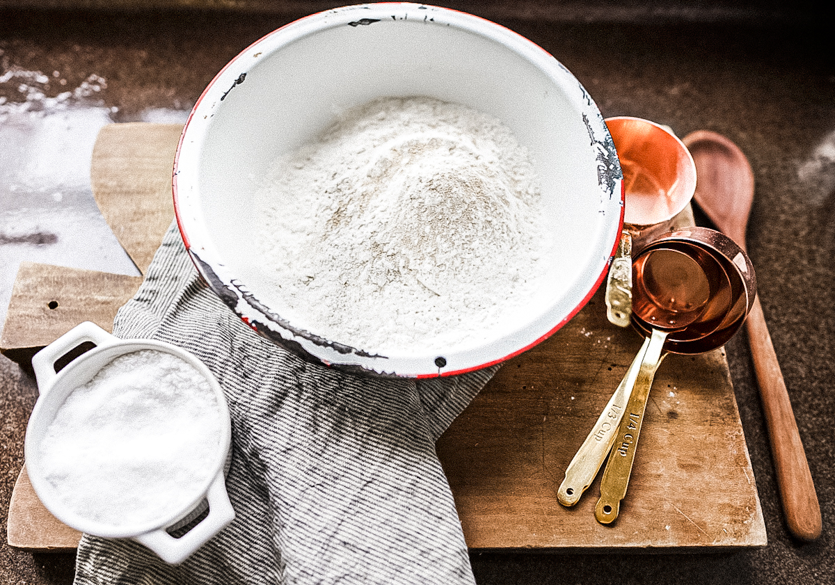 flour in vintage enamel bowl with copper measuring cups to make Parisian Baguette