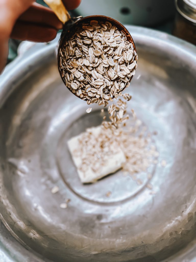 Making the oat crumble mixture for the date slice recipe. Adding oats to softened butter.