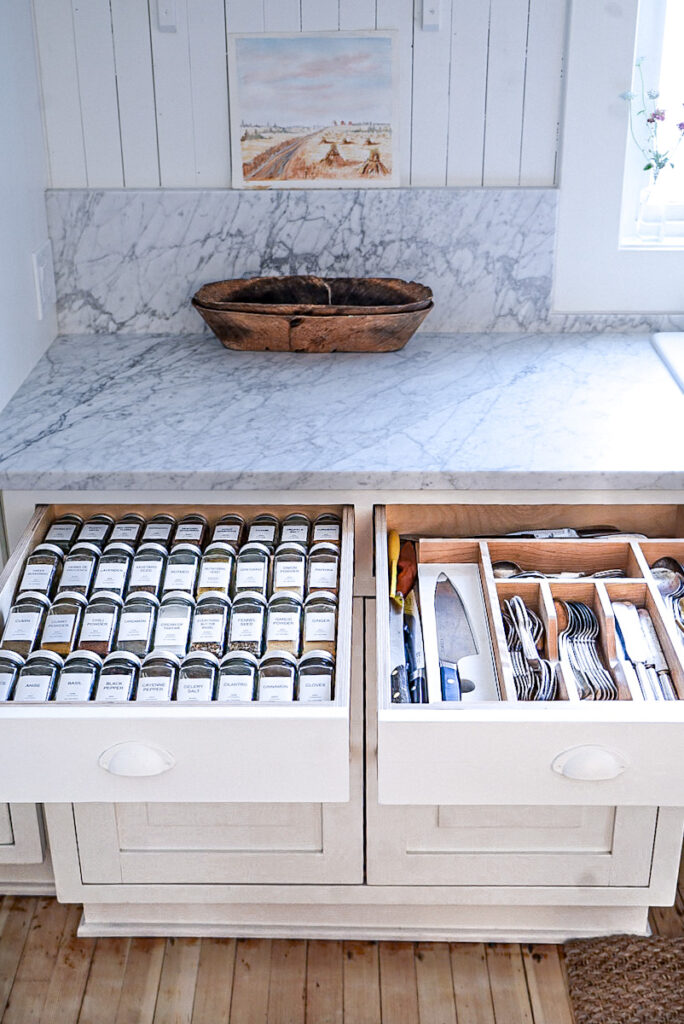Spice drawer and cutlery drawer that are extremely organized with spice jars labeled and drawer organizers.