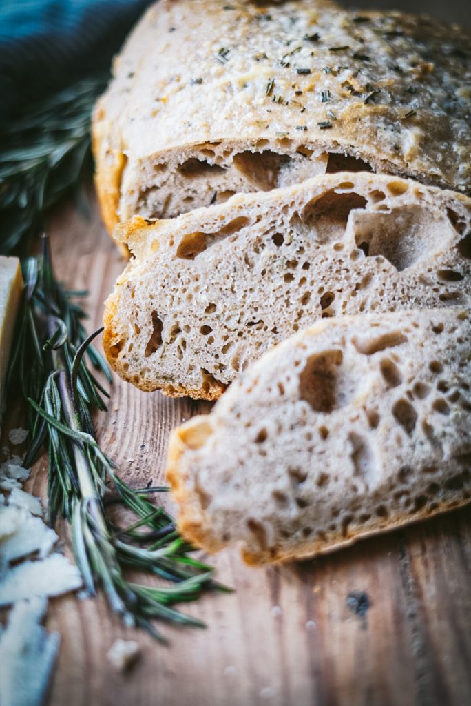 Beautiful rosemary parmesan bread that has just come out of the oven and is sliced perfectly.