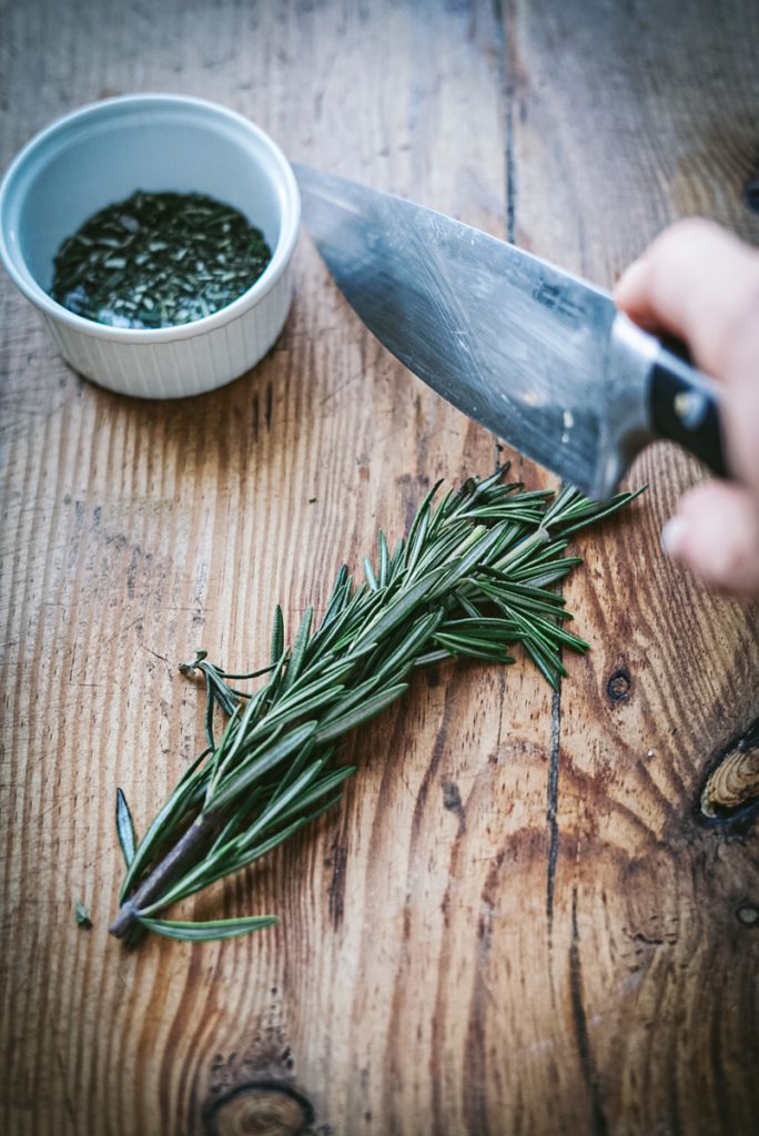 Cutting fresh rosemary to make bread.