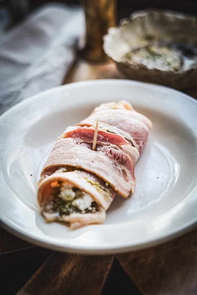 A cooking toothpick keeps the bacon  from unwrapping on a stuffed chicken breast.