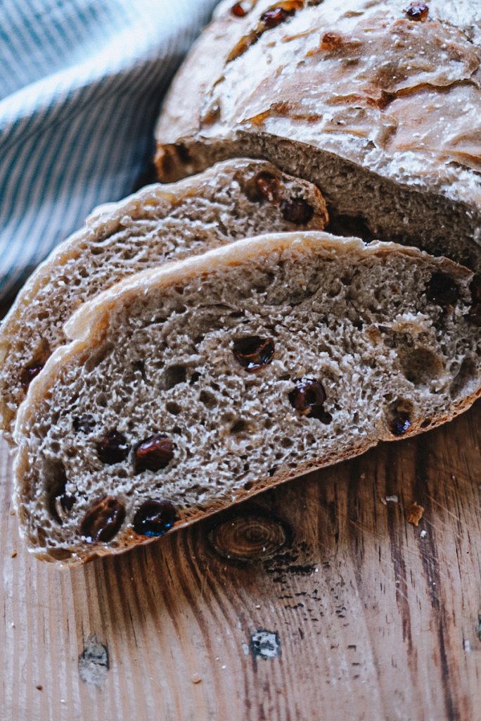 Sliced cinnamon raisin bread on a wooden cutting board.