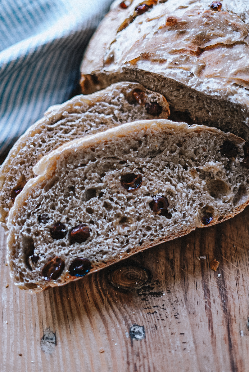 Sliced cinnamon raisin bread on a wooden cutting board.