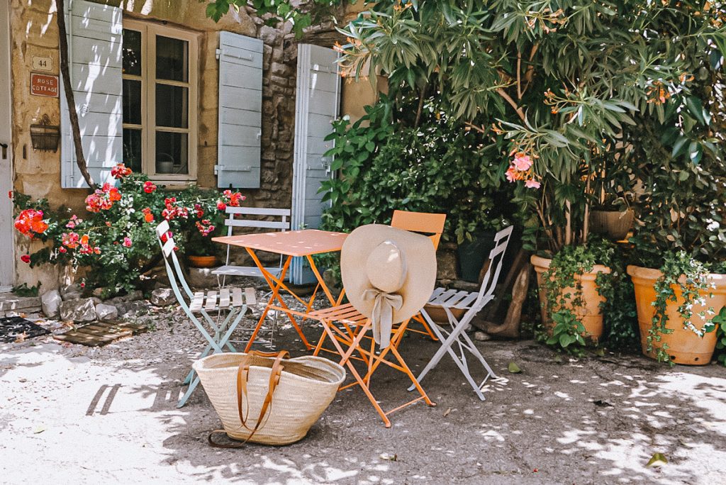 A pretty antique bistro set in a garden with a market basket and garden hat.