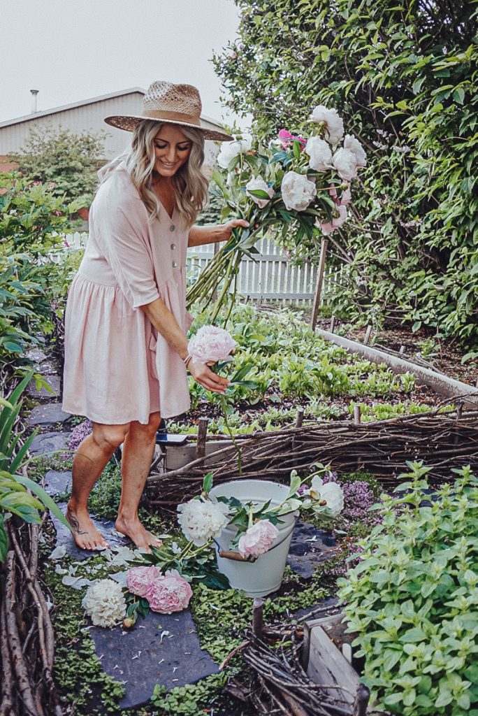 Deb from B Vintage Style harvesting peonies in a garden.