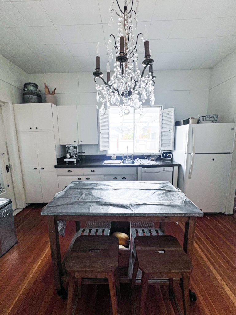 A white kitchen with an island that has a galvanized tin top.