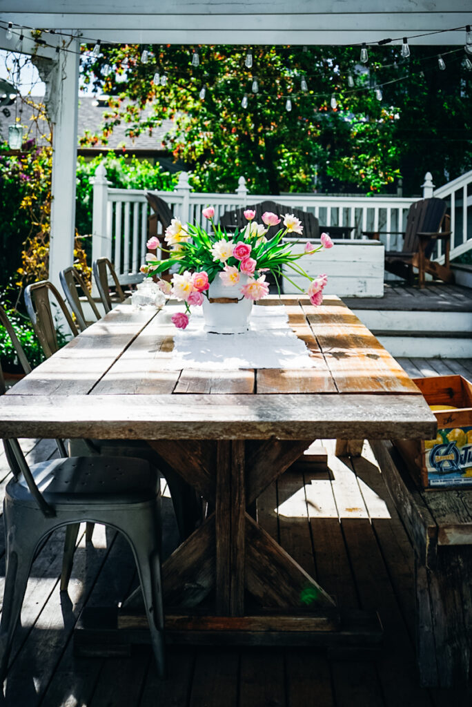 Outdoor farmhouse dining table with tulips on it.