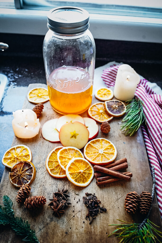 Ingredients to make homemade apple cider, including:
- apple slices
- orange slices
- star anise
- cloves
- cinnamon sticks.