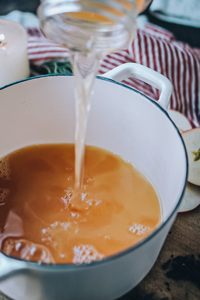 Adding homemade apple juice into a pot to make delicious, homemade cider.